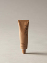Beige tube of Neroli & Patchouli hand cream on a light gray background