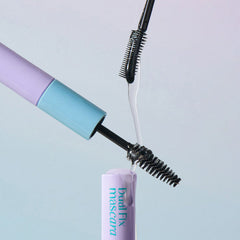 Close-up of Dual Fix mascara with visible brush and purple and blue packaging on a light gray background