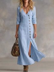 Woman wearing a light blue dress with a button front and a slit, holding a brown handbag against a neutral background.