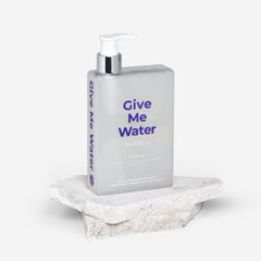 Bottle of 'Give Me Water' on a stone surface with a white background