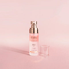 Skincare serum bottle with cap on a pink background
